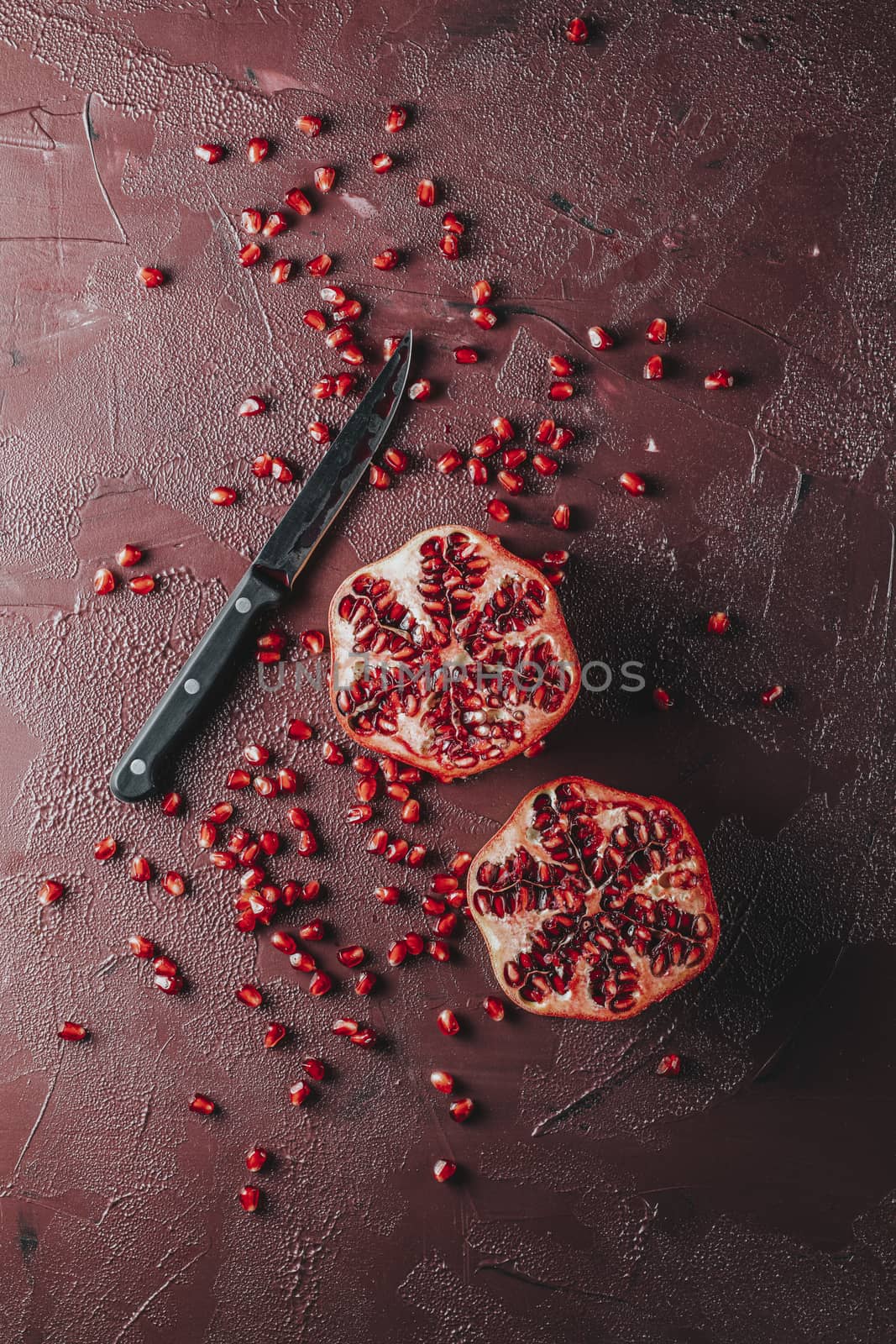 Fresh juicy pomegranate - whole and cut on a dark claret concrete vintage background, top view, horizontal, with copy space