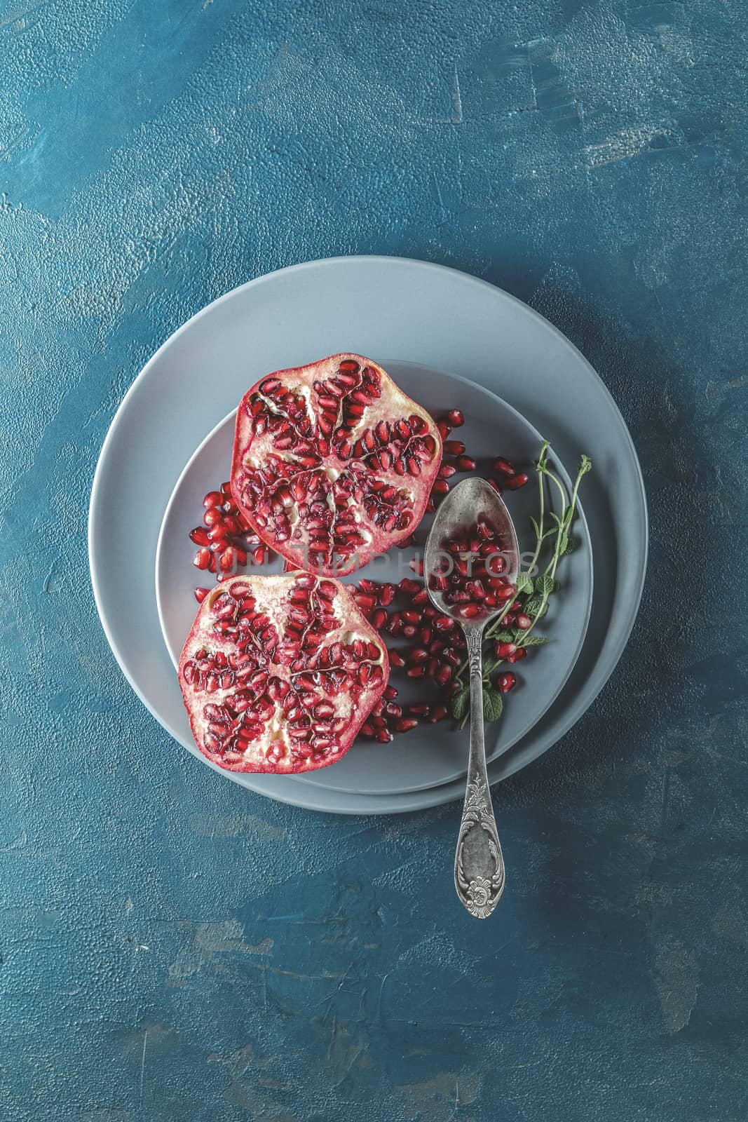 Fresh juicy pomegranate - whole and cut on a dark blue vintage background, top view, horizontal, with copy space	