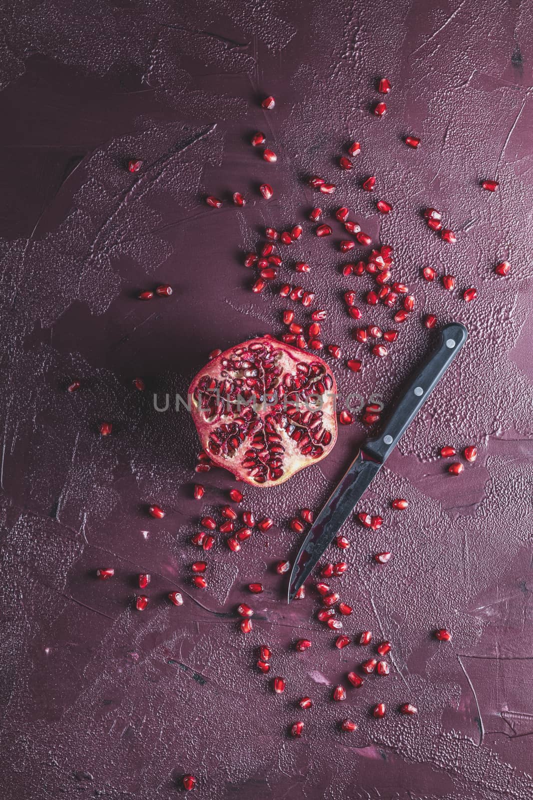 Fresh juicy pomegranate - whole and cut on a dark claret concrete vintage background, top view, horizontal, with copy space	