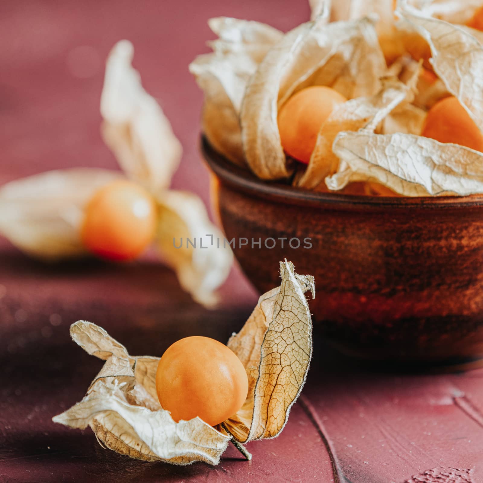 Fresh juicy group organic cape gooseberry in clay dish on dark c by ArtSvitlyna