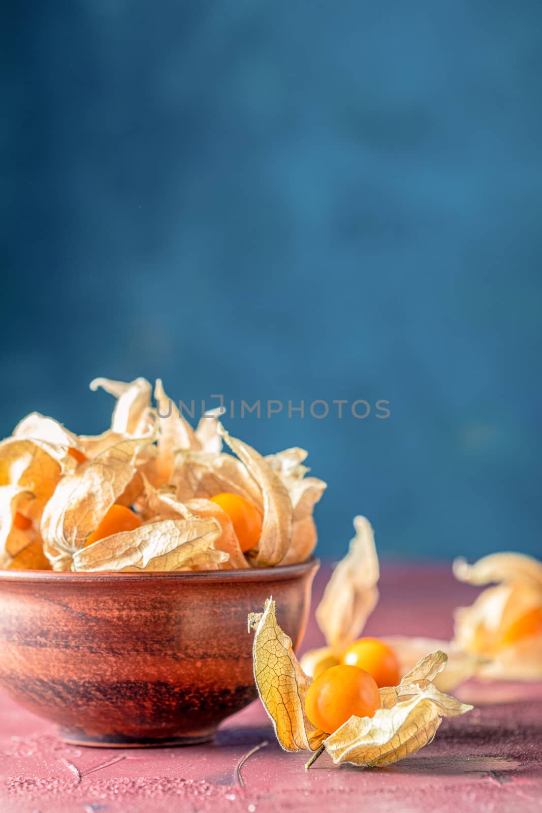 Fresh juicy group organic cape gooseberry in clay dish on dark c by ArtSvitlyna