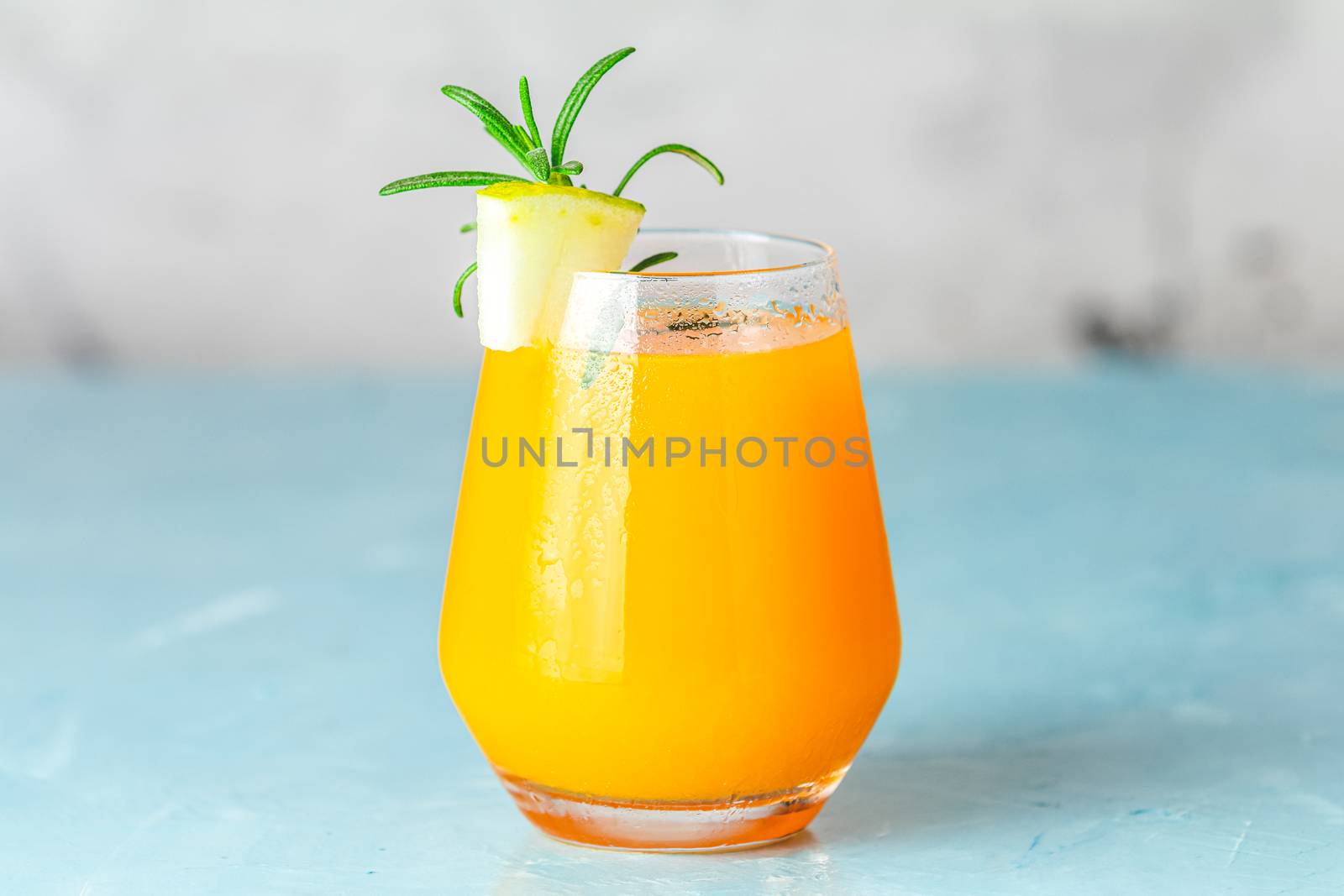 Yellow orange cocktail with melon and mint in glass on blue concrete background, close up. Summer drinks and alcoholic cocktails. Alcoholic or detox cocktail