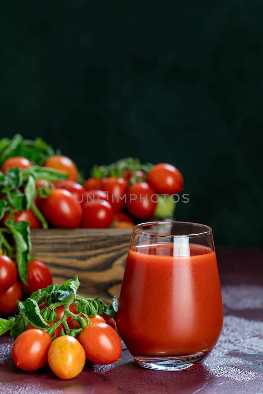 Glass of fresh delicious jummy red tomato juice and fresh tomatoes in wooden box. Dark background. Close up. Gmo free. Natural good food
