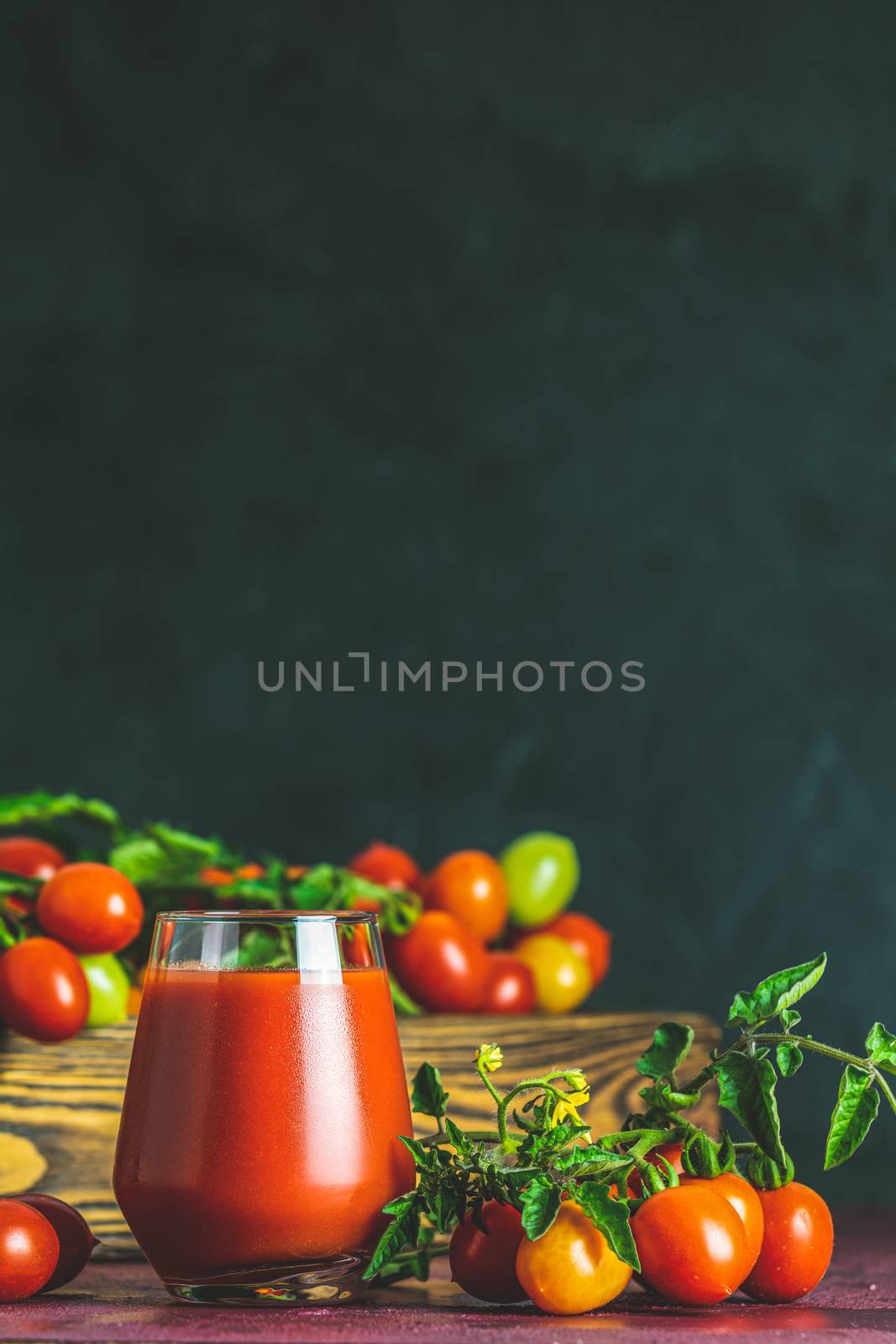 Glass of fresh delicious jummy red tomato juice and fresh tomatoes in wooden box. Dark background. Close up. Gmo free. Natural good food