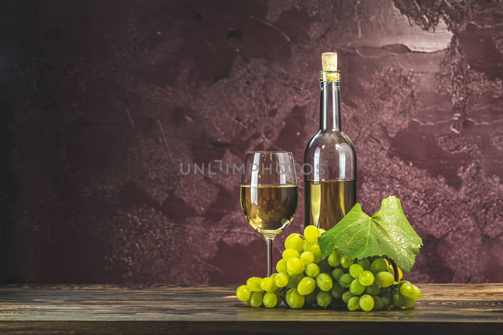 Glasses and bottles of wine and grapes on dark claret bordeaux concrete surface background