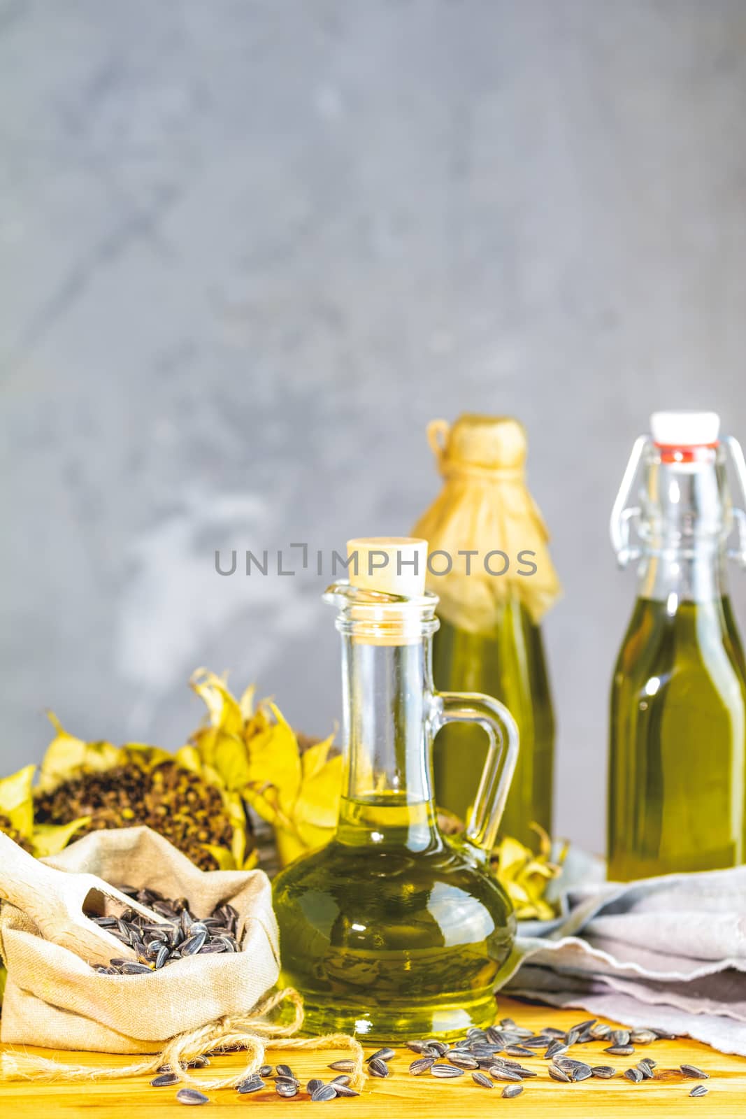 Various types of oil in bottles, dried sunflowers and seeds on w by ArtSvitlyna