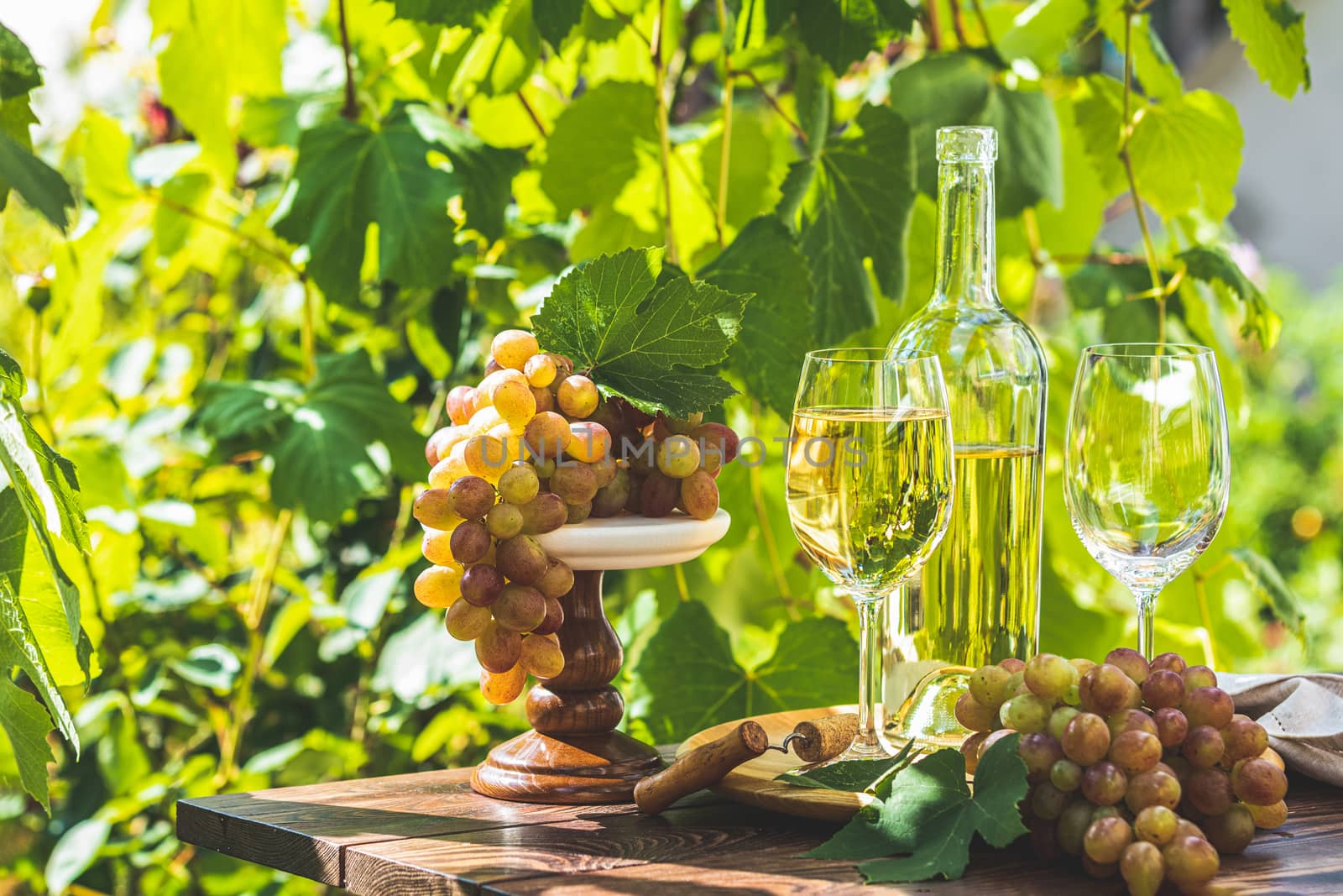 Grape and white wine. Green grape and white wine in vineyard. Sunny garden with vineyard background, summer mood concept, selective focus