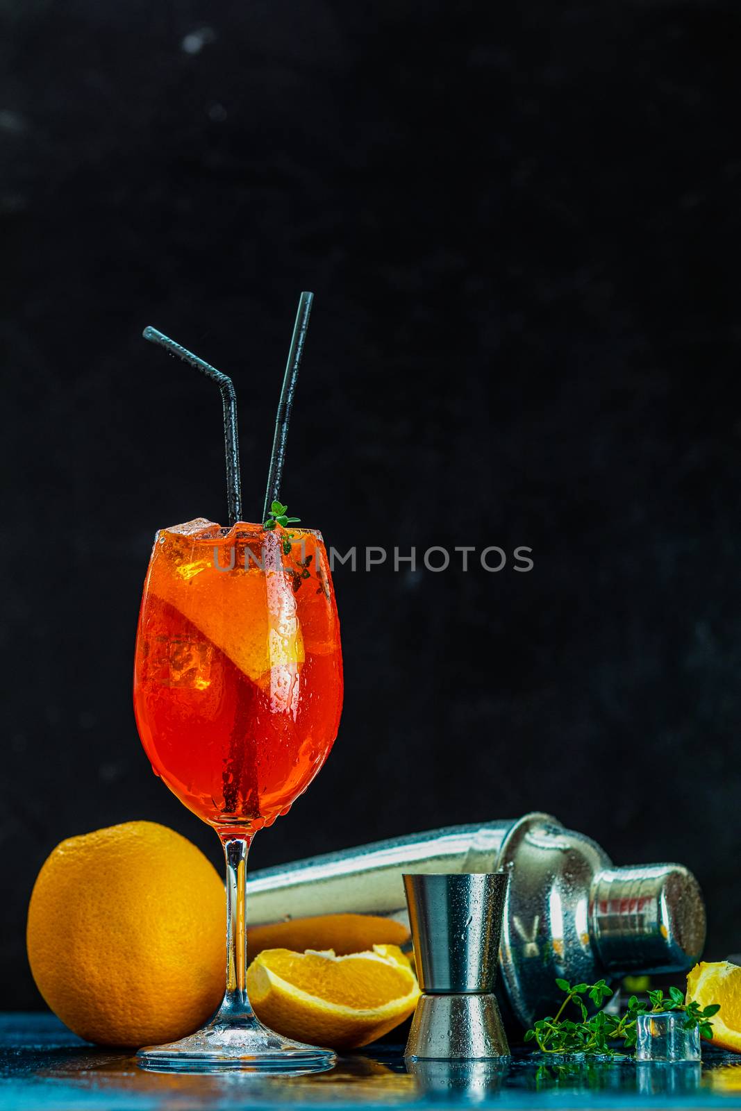 Cocktail aperol spritz in big wine glass with water drops on dark background. Summer alcohol cocktail with orange slices. Italian cocktail aperol spritz on slate board. Trendy beverage