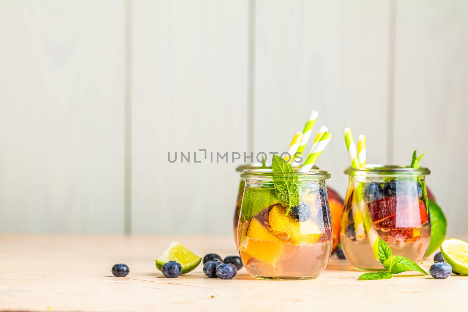 Blueberry and peach infused water, cocktail, lemonade or tea. Summer iced cold drink with blueberry, lime, peach and mint. Selective focus.