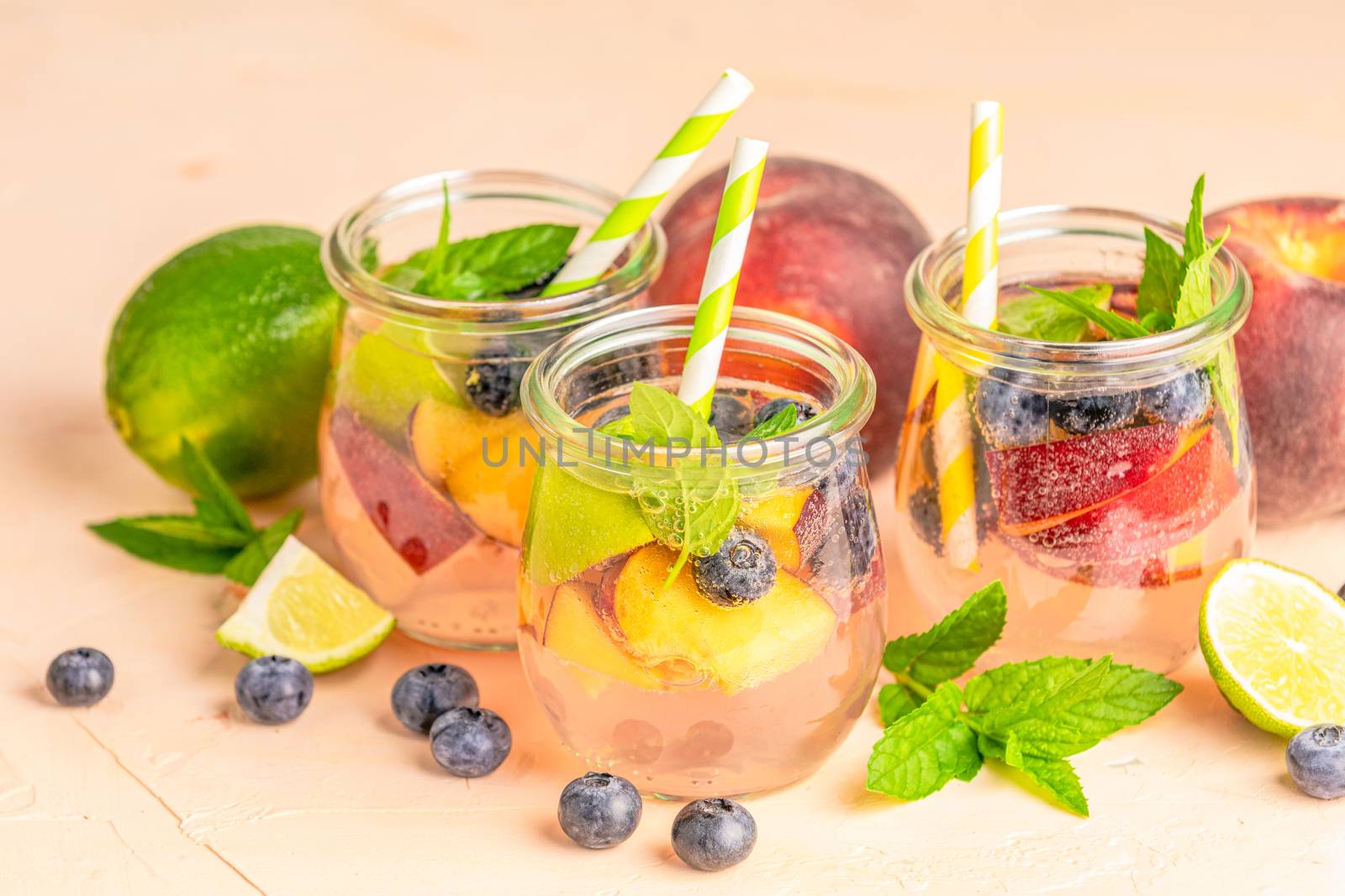 Blueberry and peach infused water, cocktail, lemonade or tea. Summer iced cold drink with blueberry, lime, peach and mint. Selective focus.