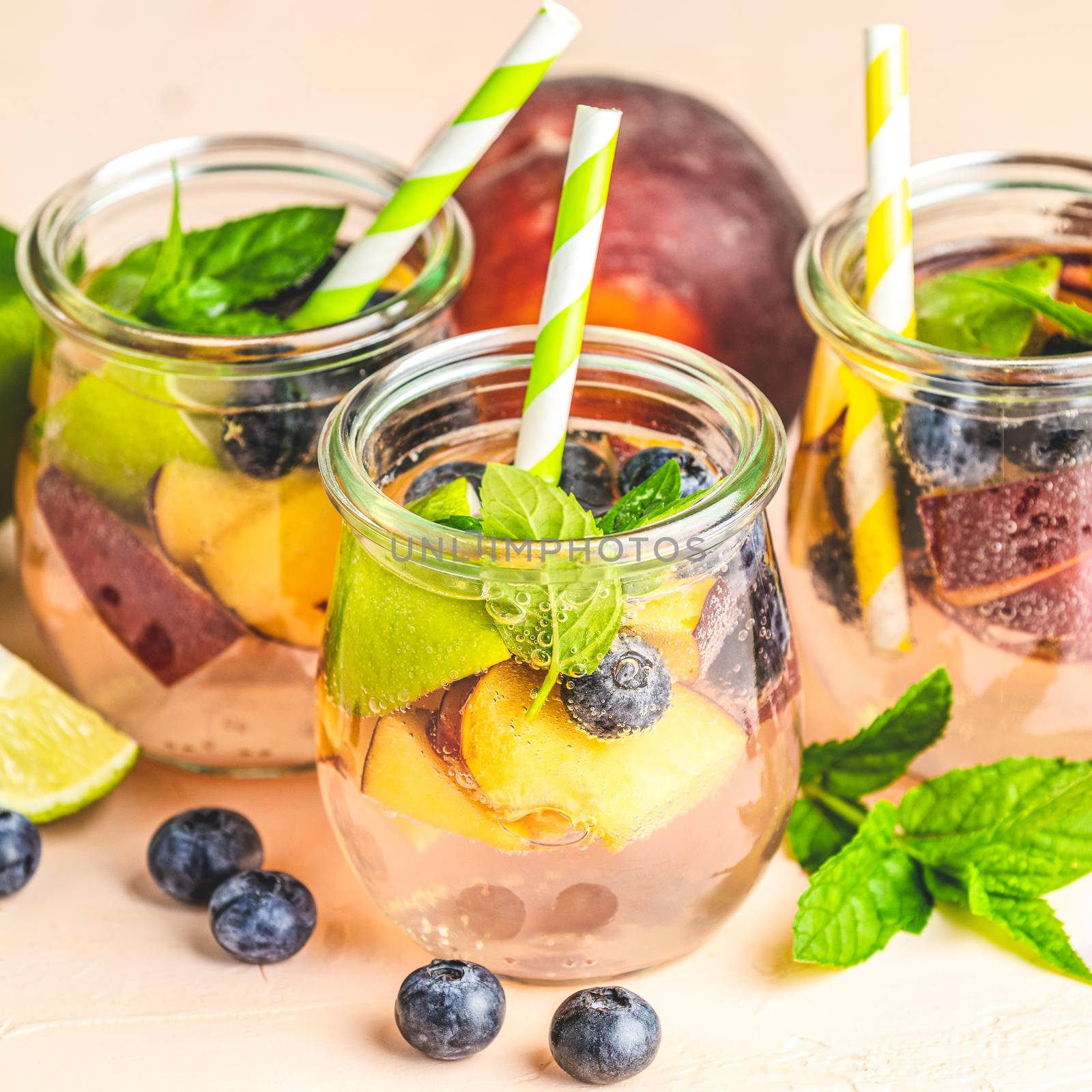 Blueberry and peach infused water, cocktail, lemonade or tea. Summer iced cold drink with blueberry, lime, peach and mint. Selective focus.