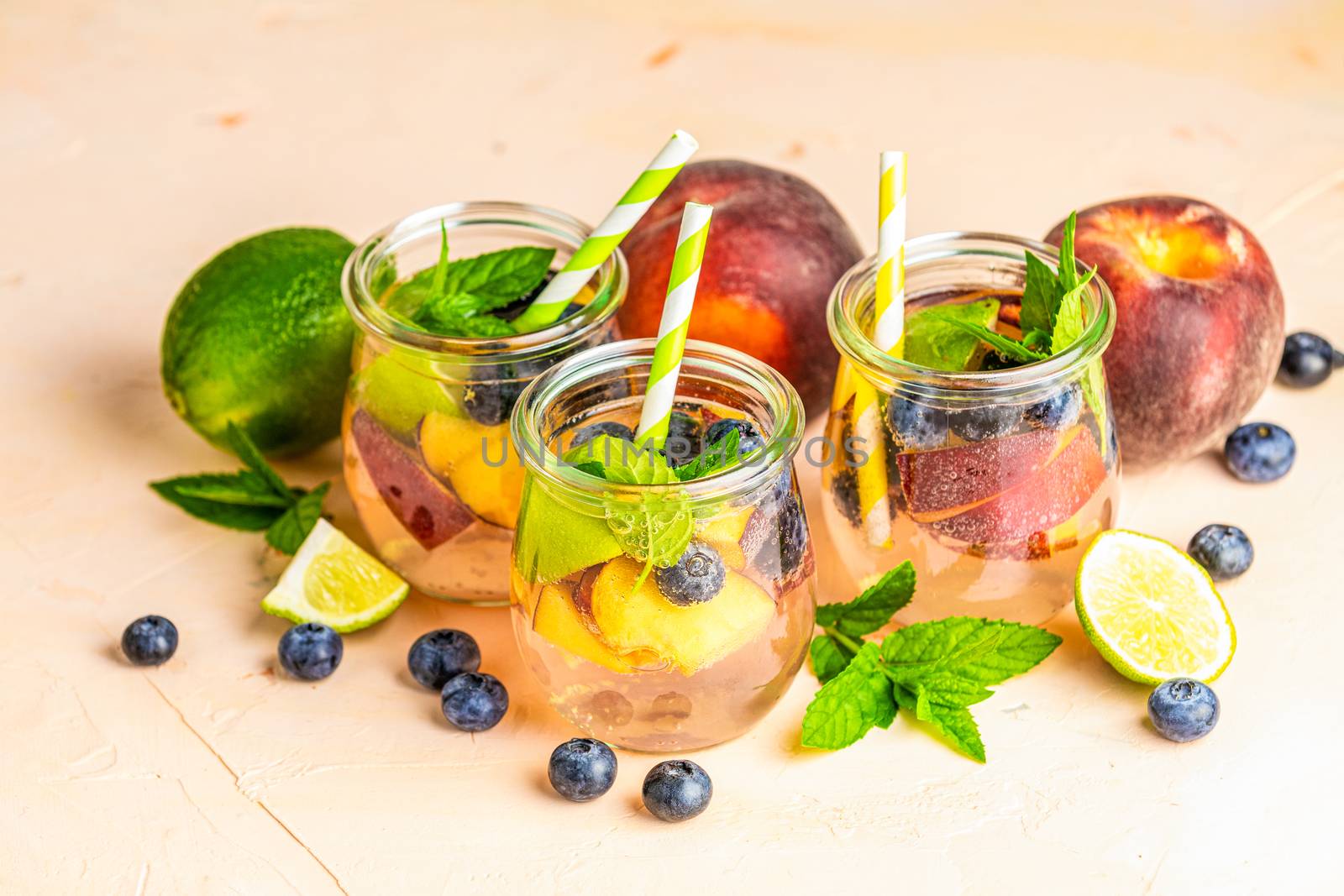 Blueberry and peach infused water, cocktail, lemonade or tea. Summer iced cold drink with blueberry, lime, peach and mint. Selective focus