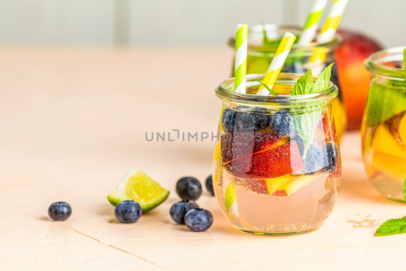 Blueberry and peach infused water, cocktail, lemonade or tea. Summer iced cold drink with blueberry, lime, peach and mint. Selective focus.