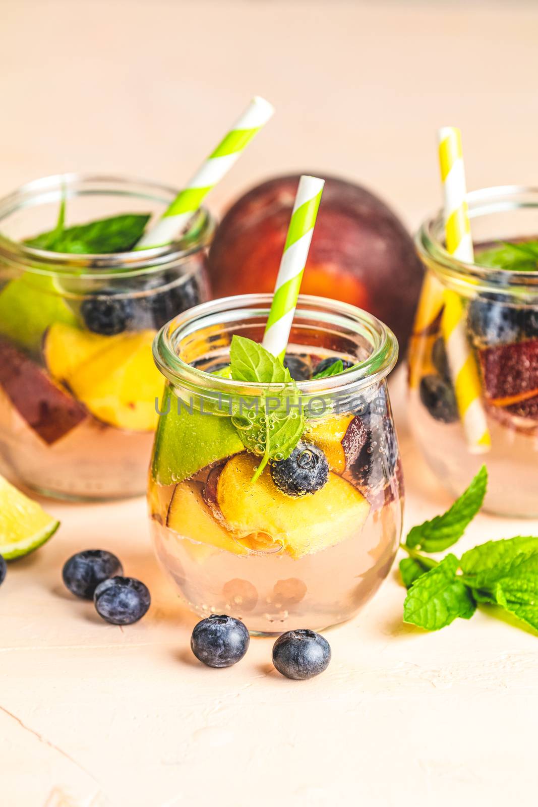 Blueberry and peach infused water, cocktail, lemonade or tea. Summer iced cold drink with blueberry, lime, peach and mint. Selective focus