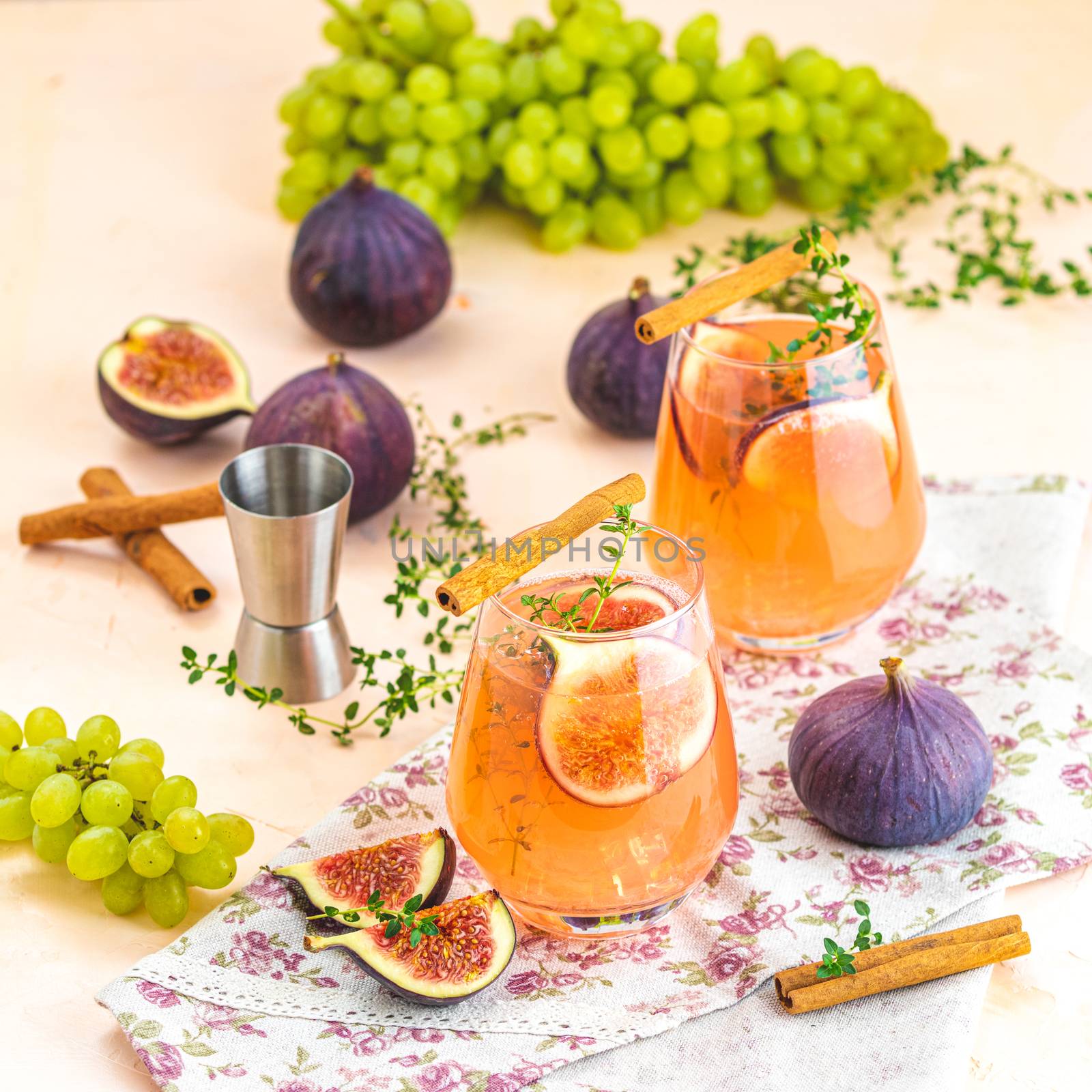 Pink cocktail with fig, thyme, cinnamon and grapes in glass on pink concrete background, close up. Autumn drinks and alcoholic cocktails. Alcoholic cocktail or detox drink