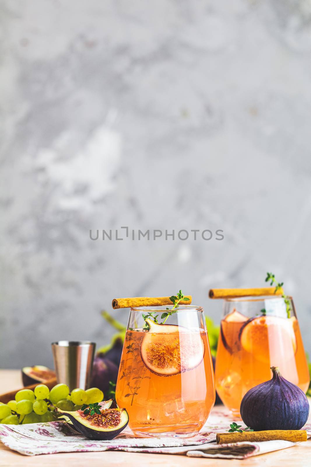 Pink cocktail with fig, thyme, cinnamon and grapes in glass on pink concrete background, close up. Autumn drinks and alcoholic cocktails. Alcoholic cocktail or detox drink