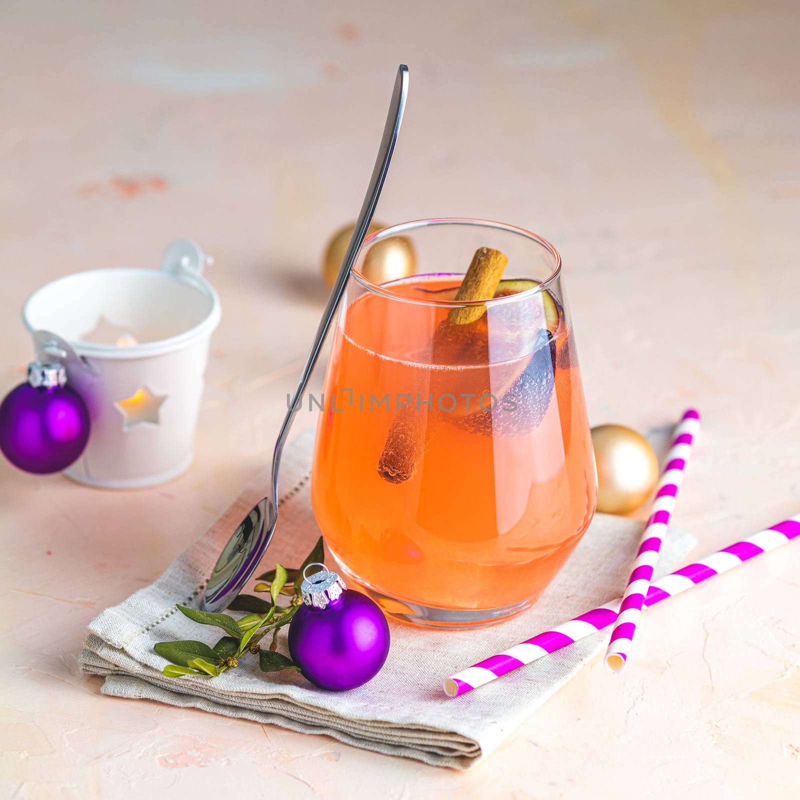 Christmas and New Year pink cocktail with fig and cinnamon  in glass on pink concrete background, close up, surrounded  holiday decor. Winter festive drinks and alcoholic cocktails or detox drink