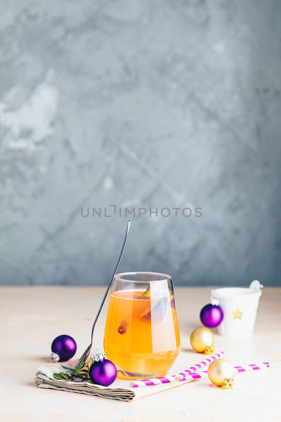 Christmas and New Year pink cocktail with fig and cinnamon  in glass on pink concrete background, close up, surrounded  holiday decor. Winter festive drinks and alcoholic cocktails or detox drink