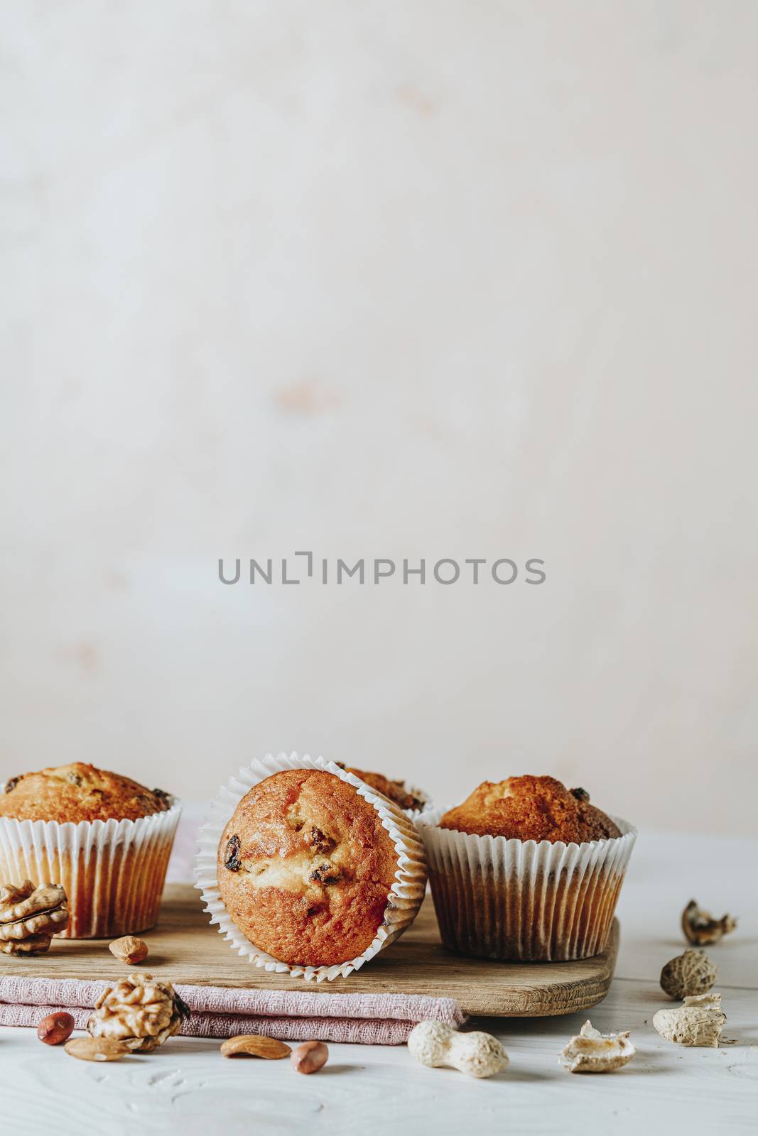 Vanilla caramel muffins in paper cups on white wooden background by ArtSvitlyna