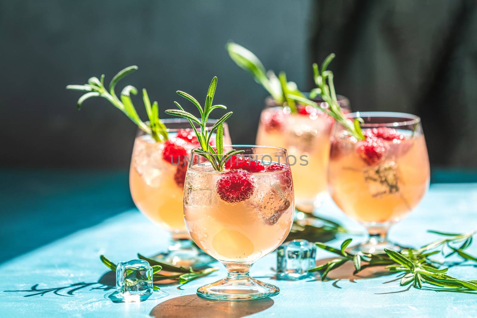 Pink drink with ice. Close up mix berries ice soda with thyme in a transparent glass on white table at cafe.Summer cold Welcome drink and cocktail. Holiday, sunny light