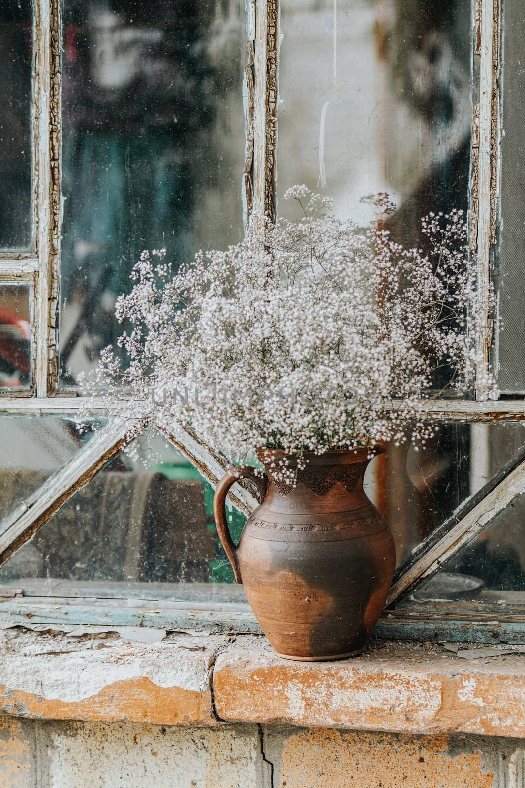 Beautiful retro still life with wild flowers in clay jug on windowsill of an old window. Close up, shallow depth of the field, copy space for you text.