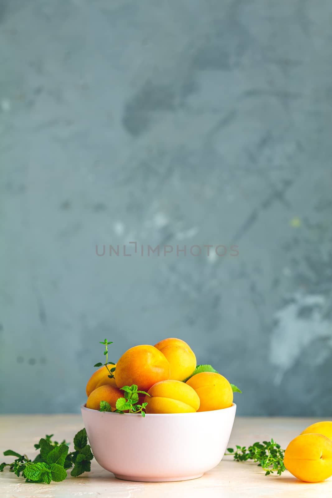 Fresh sweet orange apricots in pink bowl on the pink concrete su by ArtSvitlyna