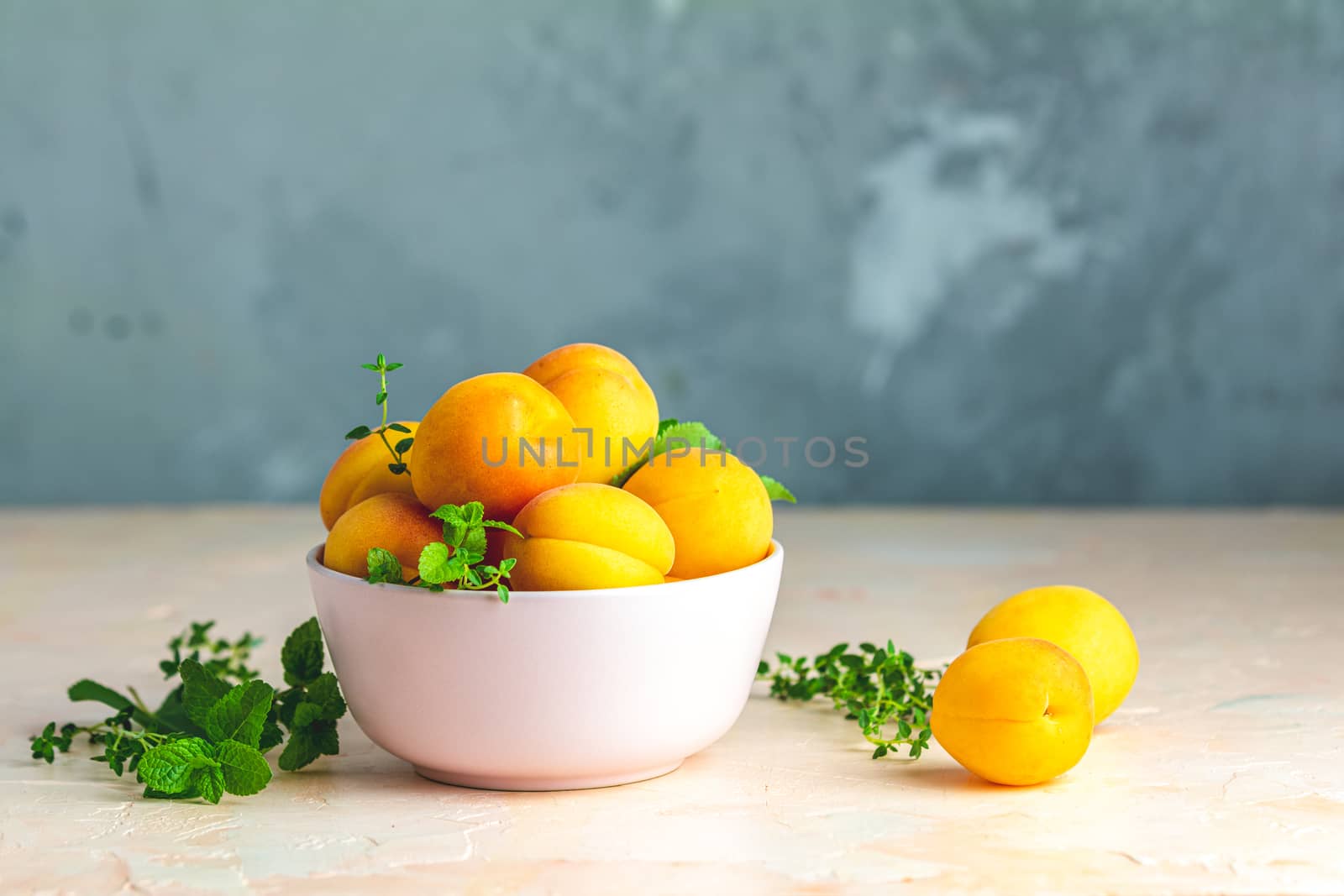 Fresh sweet orange apricots in pink bowl on the pink concrete surface table, selective focus, shallow depth of the fields