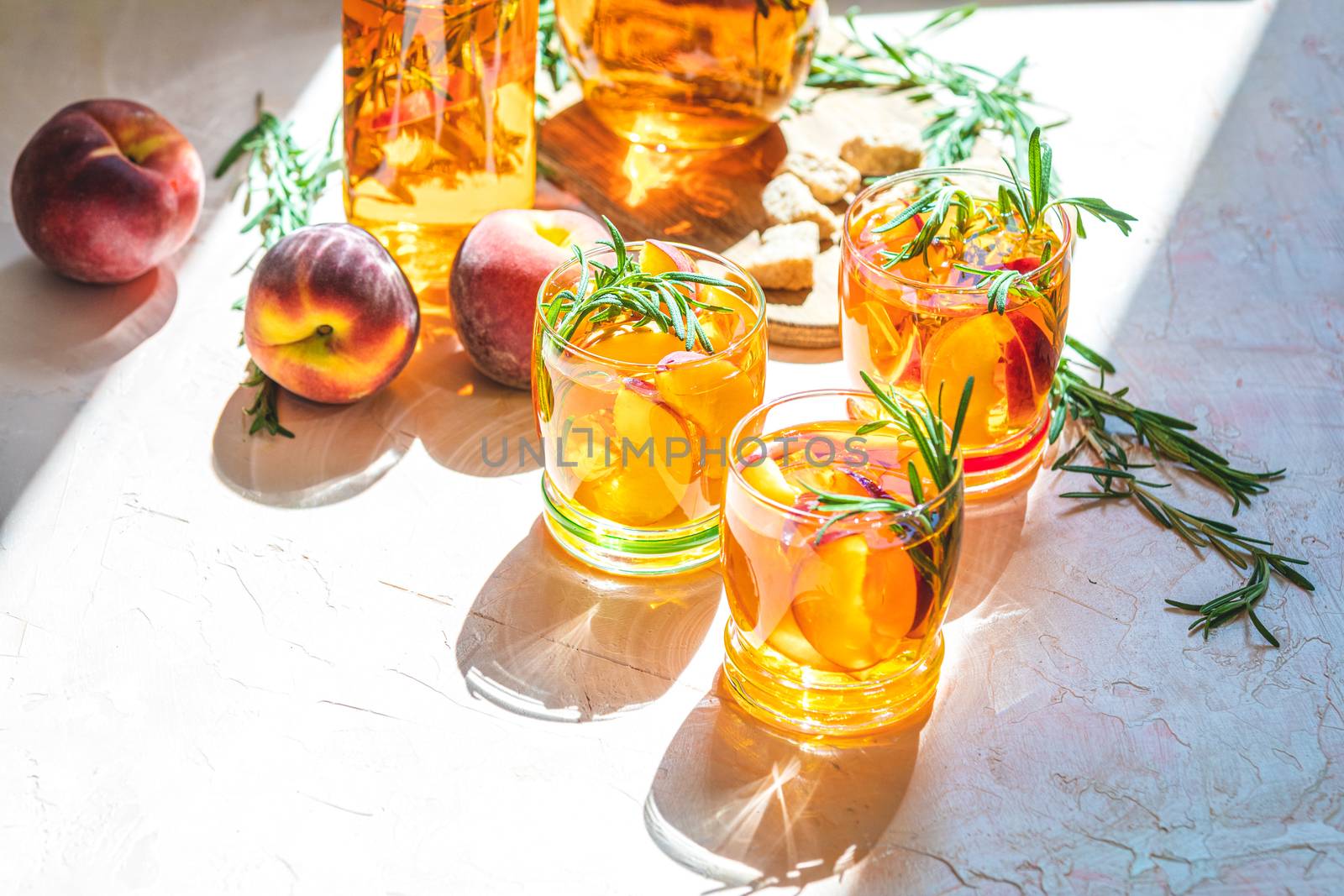 Summer cold peach fizz cocktail or iced tea with rosemary. Sunny light. Shallow depth of the field, close up, copy space for you text.