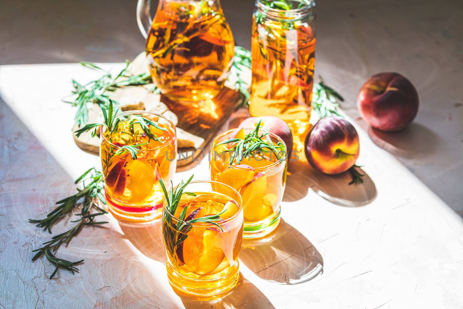 Glasses of sweet peach iced tea, Summer cold peach fizz cocktail with rosemary. Sunny light. Shallow depth of the field, close up, copy space for you text