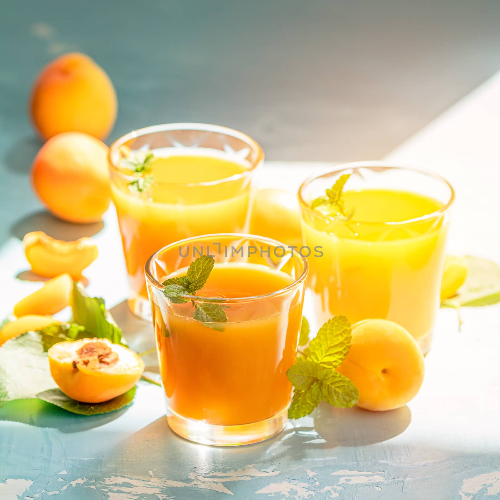 Glass of fresh healthy apricot juice in sunny light by ArtSvitlyna