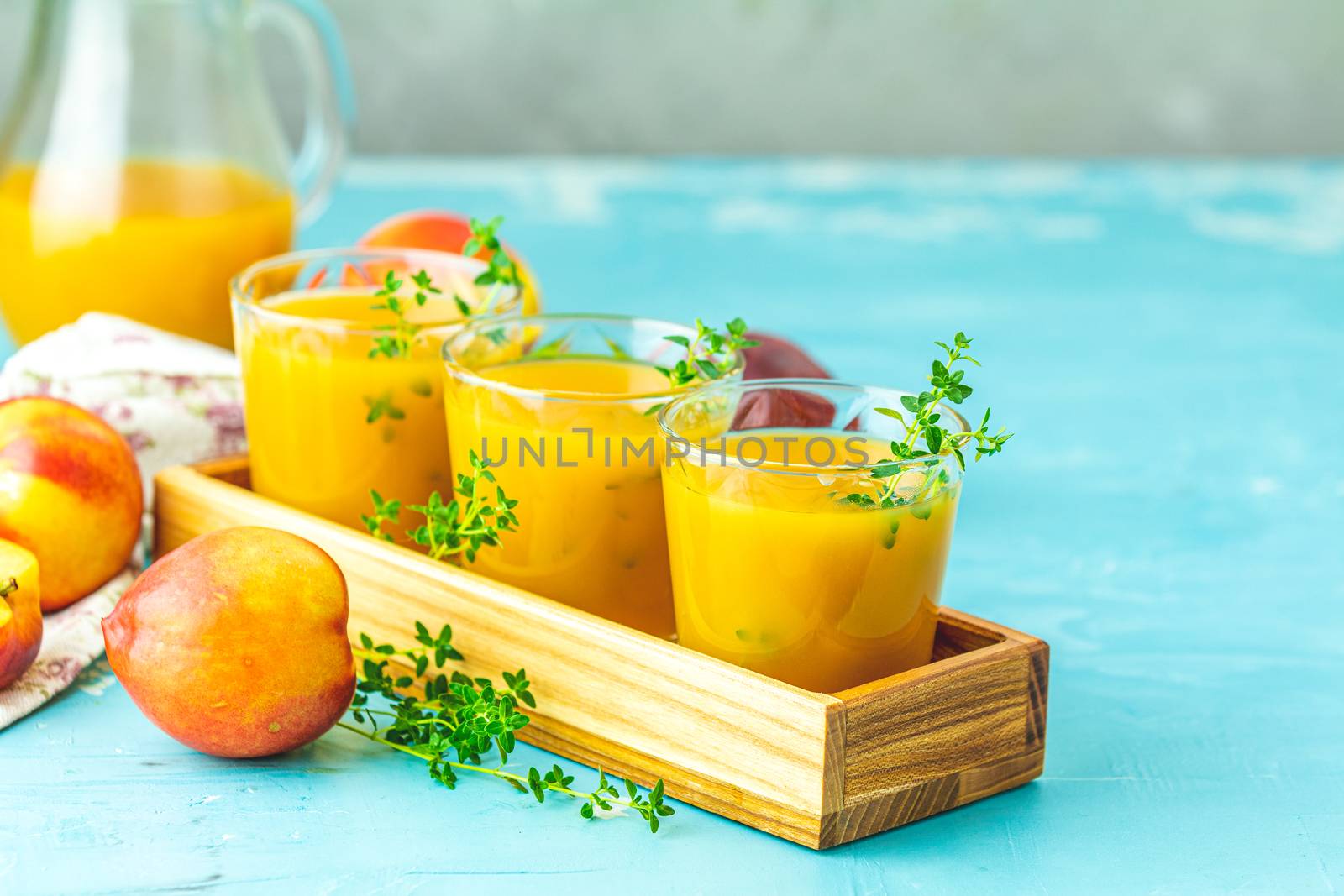 Glass of fresh healthy peach smoothie or juice in wooden box on light blue concrete surface table. Shallow depth of the field, close up, copy space for you text