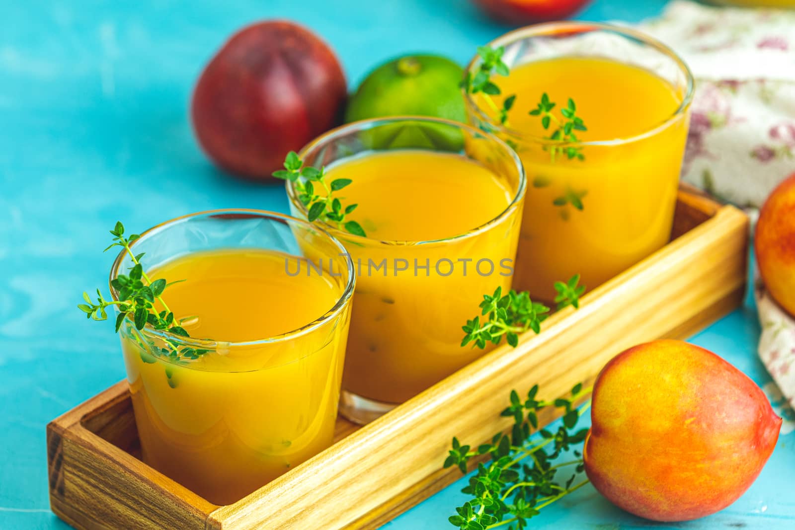 Glass of fresh healthy peach smoothie or juice in wooden box on light blue concrete surface table. Shallow depth of the field, close up, copy space for you text.