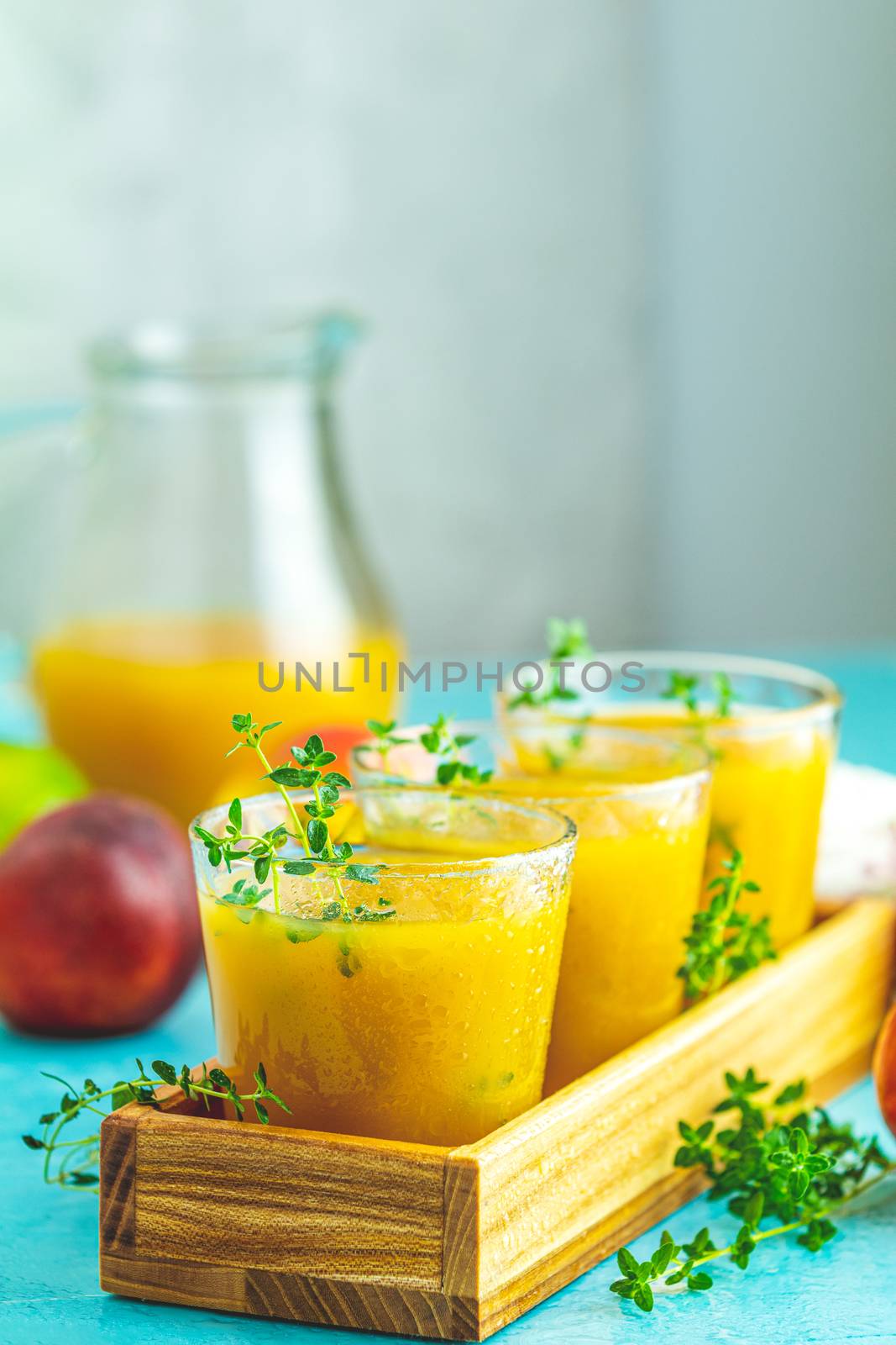 Glass of fresh healthy peach smoothie or juice in wooden box on light blue concrete surface table. Shallow depth of the field, close up, copy space for you text