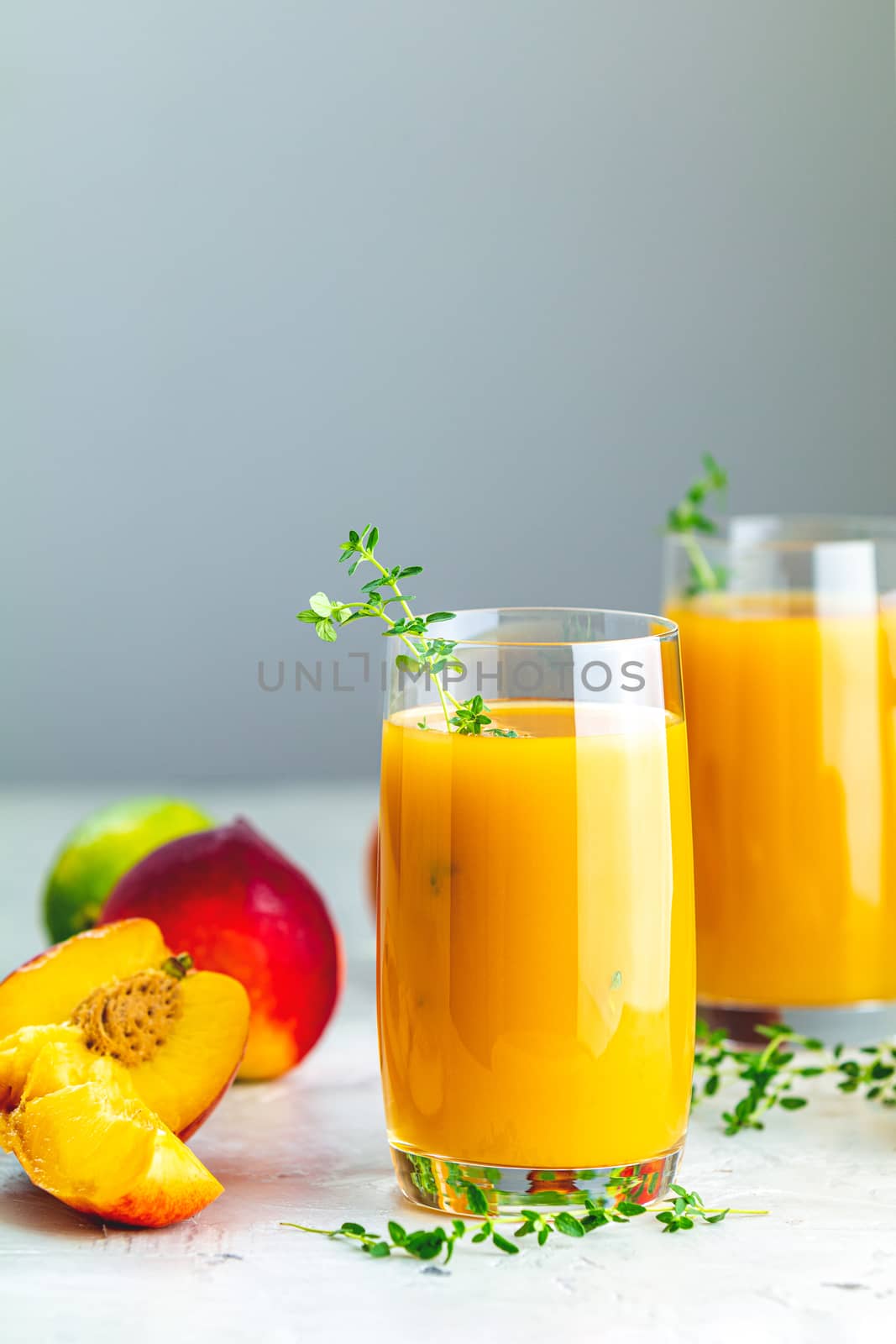 Glass of fresh healthy peach smoothie or juice on light gray concrete surface table. Shallow depth of the field, close up, copy space for you text