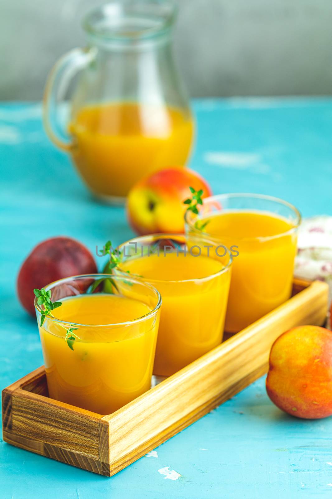 Glass of fresh healthy peach smoothie or juice in wooden box on light blue concrete surface table. Shallow depth of the field, close up, copy space for you text