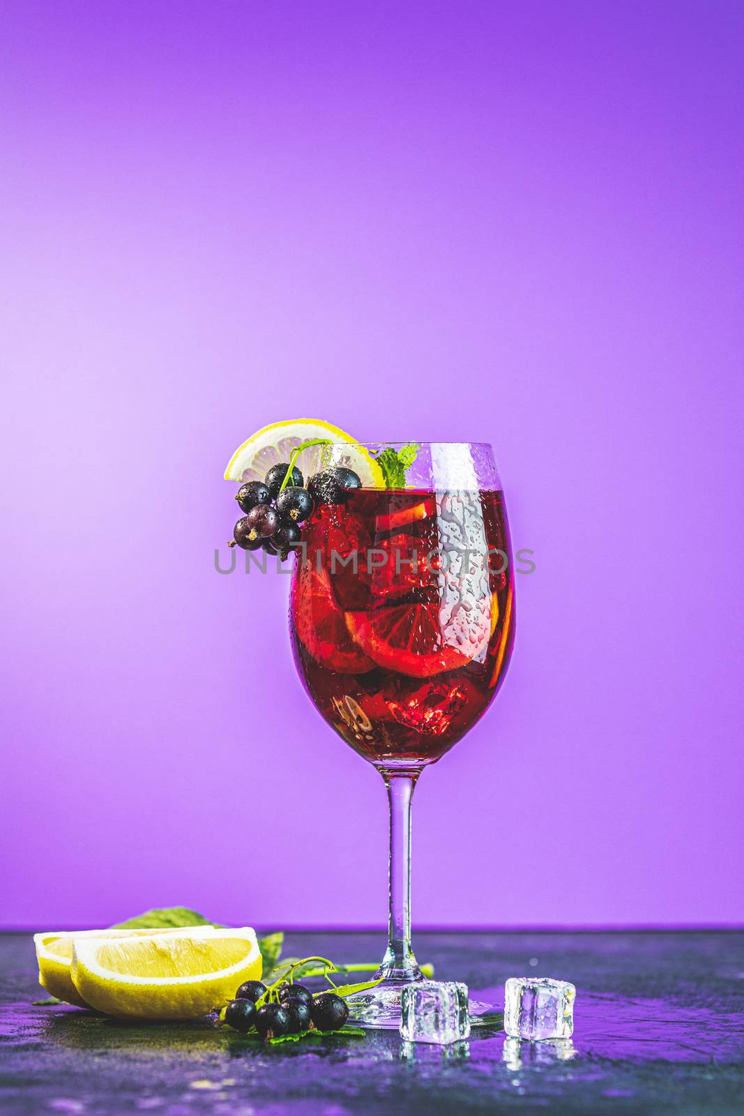 Cold red cocktail with blackcurrant, lemon, mint and ice in tall glass on violet background. Summer drinks and alcoholic cocktails. Alcoholic cocktail Blackcurrant mojito