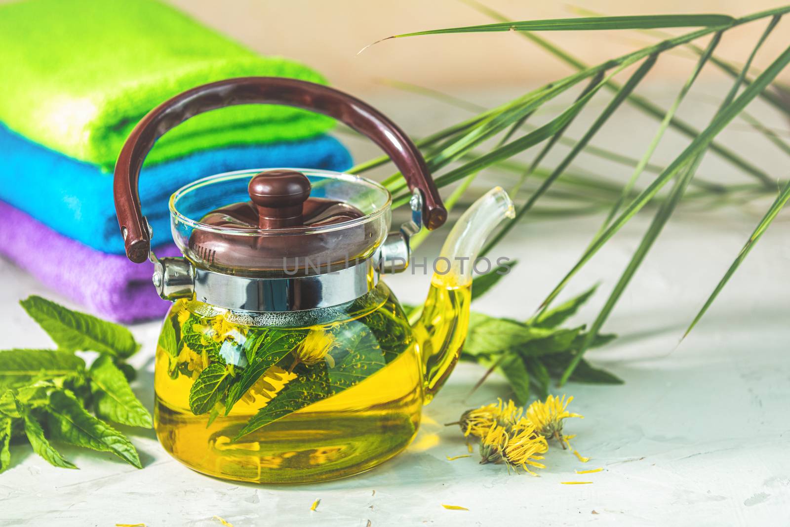 Asian tea and SPA set composition. Healthy life and relaxation concept. Glass tea pot and green tea in strainer on light gray concrete table background.