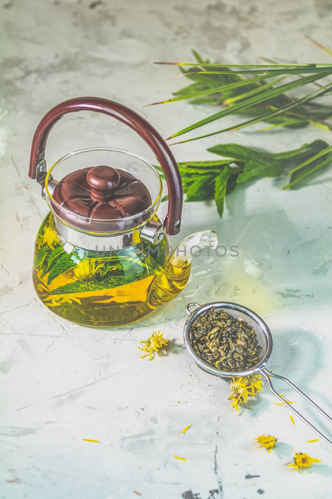 Asian tea set composition. Healthy life and relaxation concept. Glass tea pot and  green tea in strainer on light gray concrete table background.