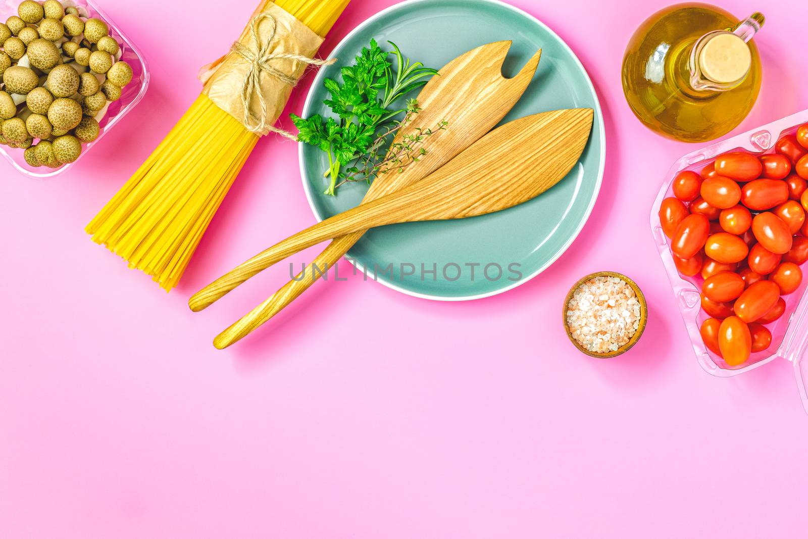 Spaghetti, shimeji mushroom, olive oil,  pink salt, empty ceramic bowl, wooden spoons for salad over pink background. Top view, flat lay, healthy food concept, copy space for you text.