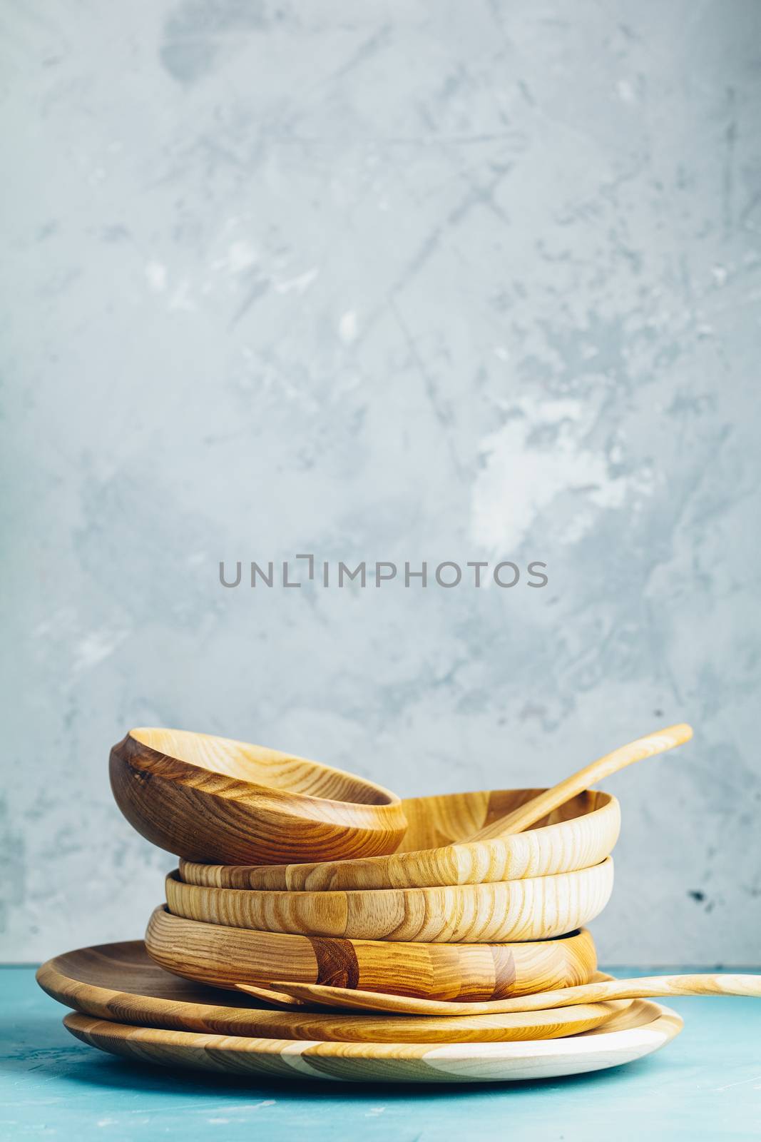 Variety of wooden bowl, wooden spoons for salad over blue texture background. Food or ecology kitchen concept. Copy space for you text.
