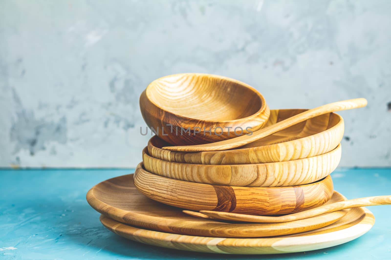 Variety of wooden bowl, wooden spoons for salad over blue texture background. Food or ecology kitchen concept. Copy space for you text.