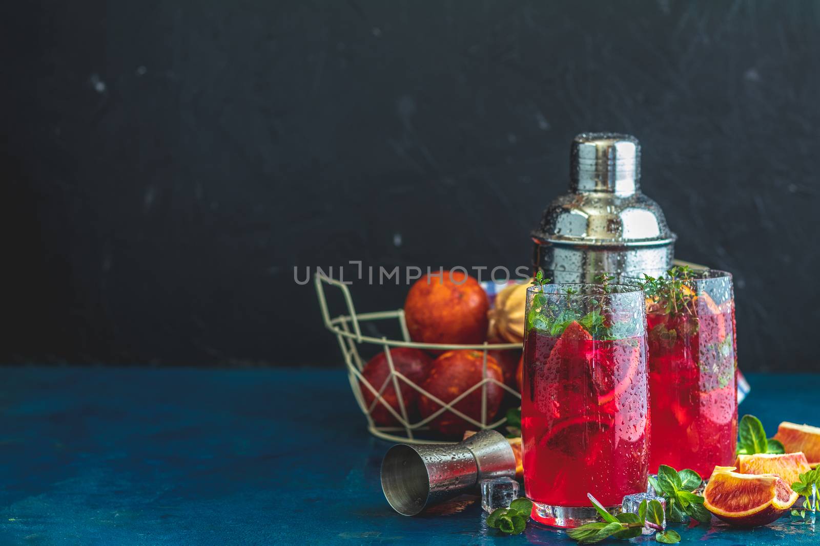 Cocktail bloody orange margarita in highball glass. Refreshing summer drinks. Cocktail blood orange margarita, in glasses on a dark blue concrete table surface with a garnish of orange. Copy space.
