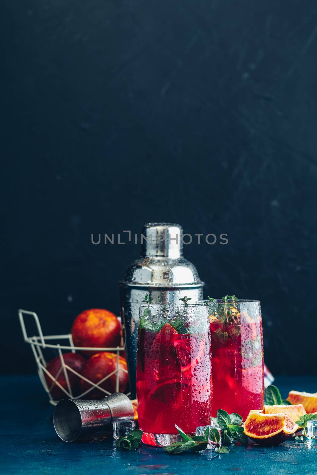 Cocktail bloody orange margarita in highball glass. Refreshing summer drinks. Cocktail blood orange margarita, in glasses on a dark blue concrete table surface with a garnish of orange. Copy space.