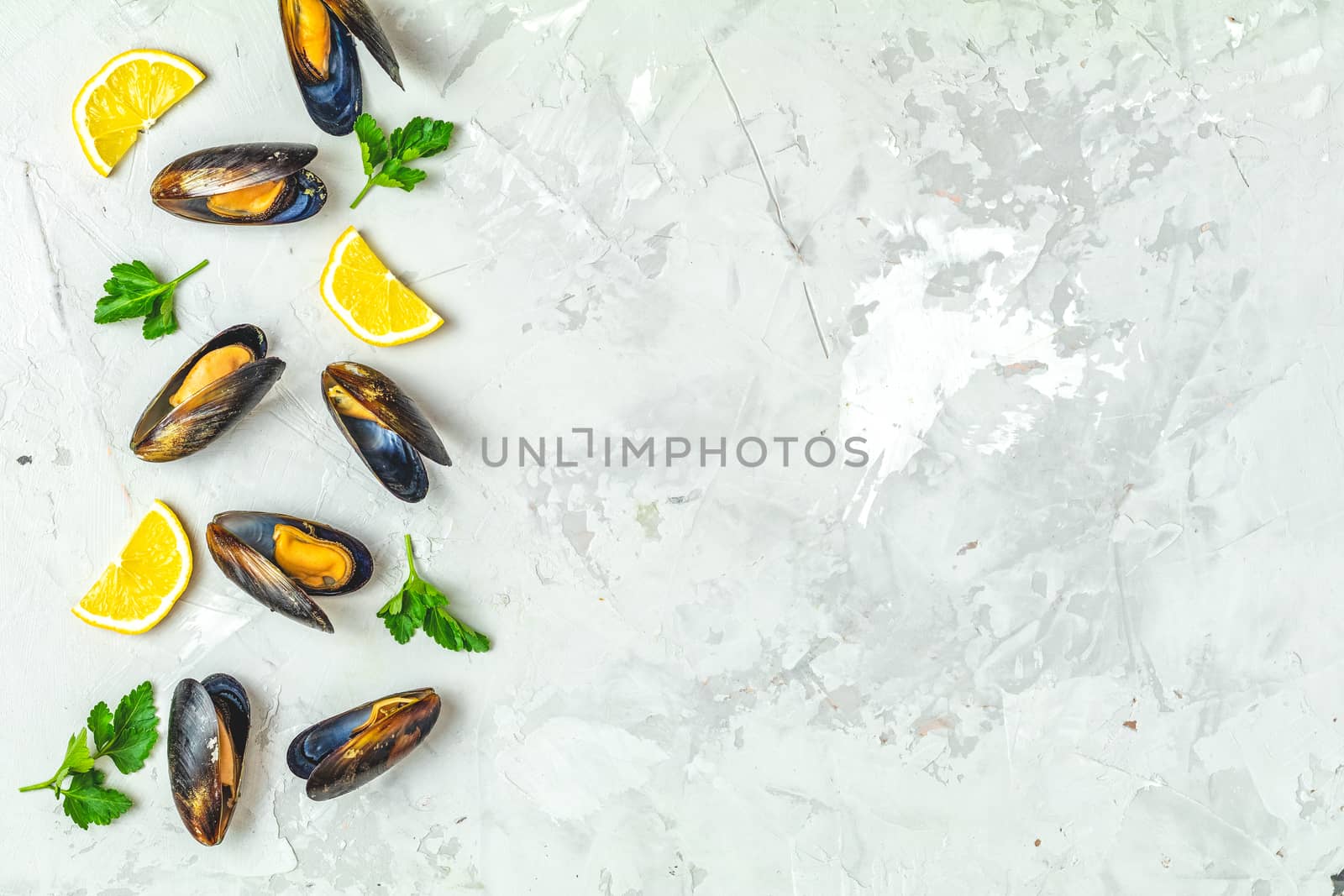 Seafood mussels with lemon and parsley on light gray concrete table surface, top view, copy space for you text. Food background