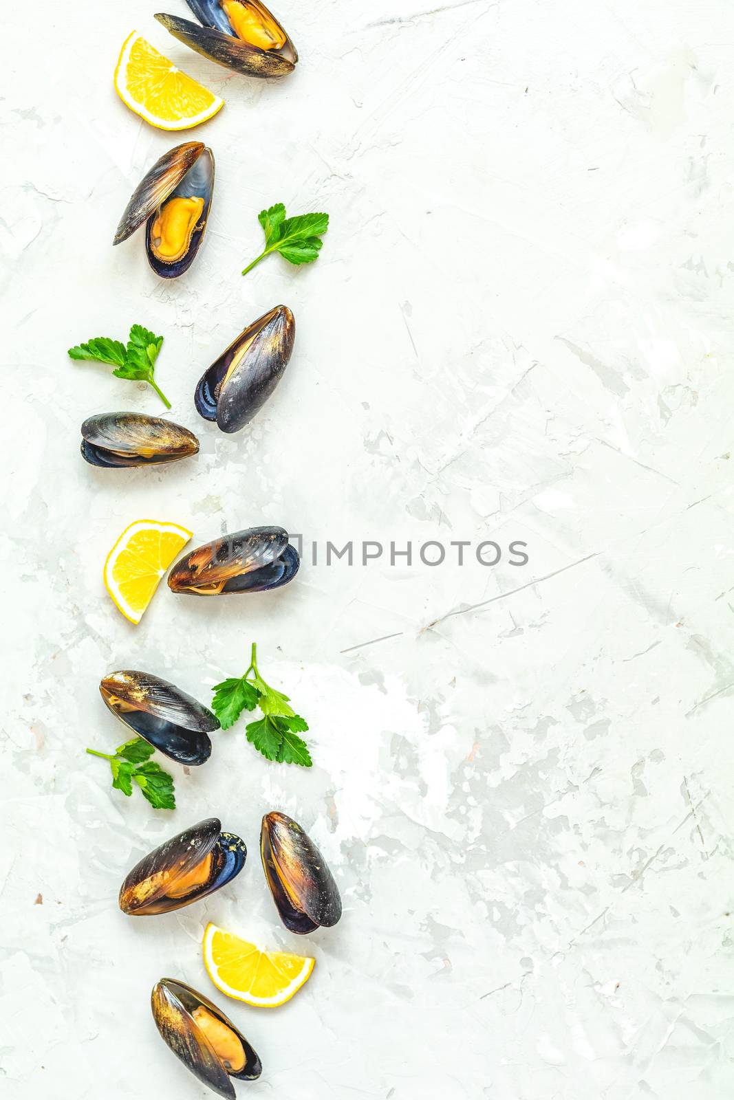 Seafood mussels with lemon and parsley on light gray concrete table surface, top view, copy space for you text. Food background