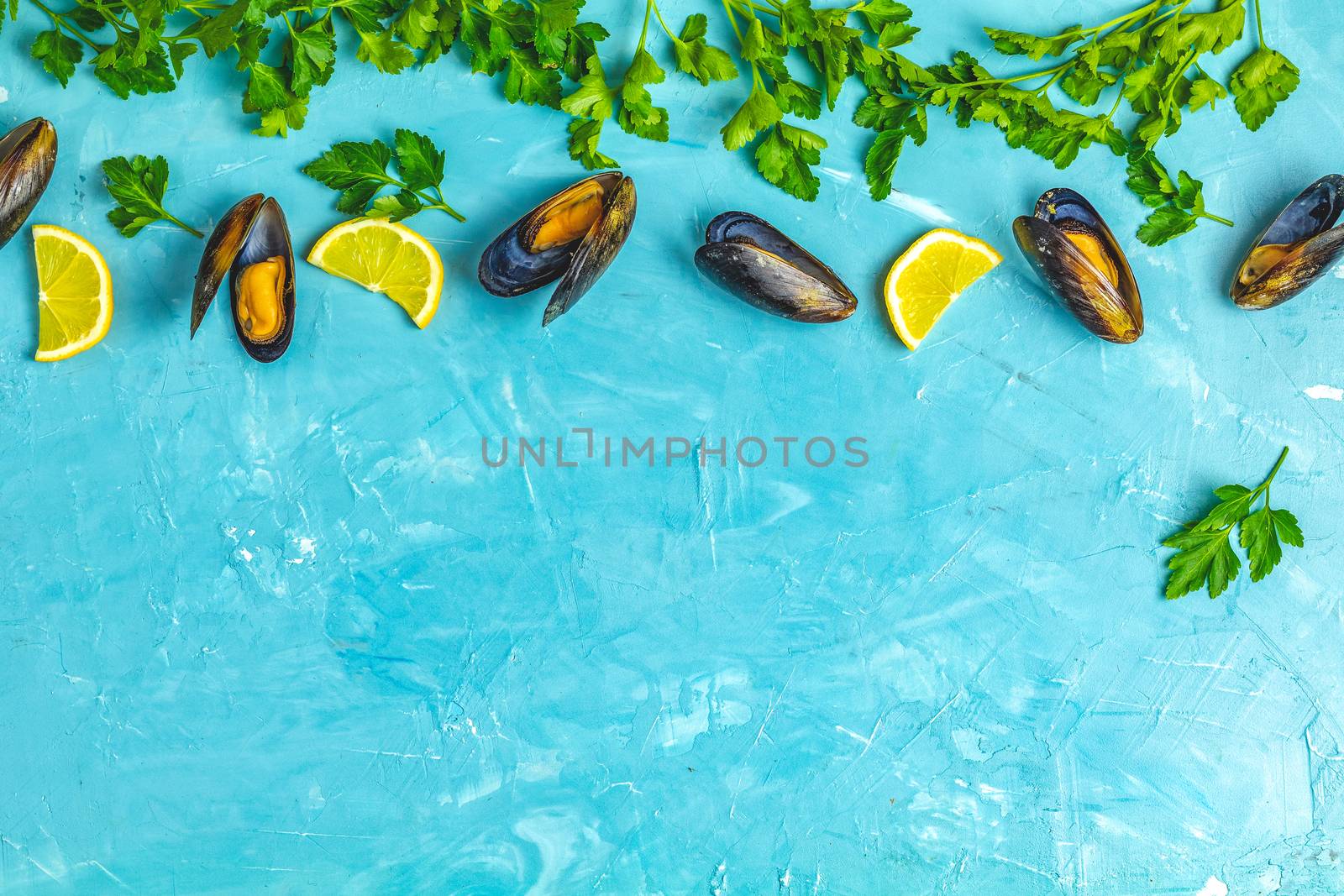 Seafood mussels with lemon and parsley on light blue concrete table surface, top view, copy space for you text