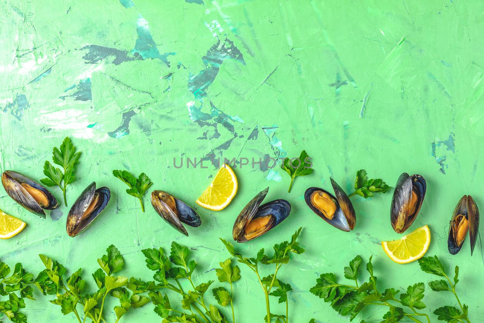 Seafood mussels with lemon and parsley on green concrete table surface, top view, copy space for you text, food background