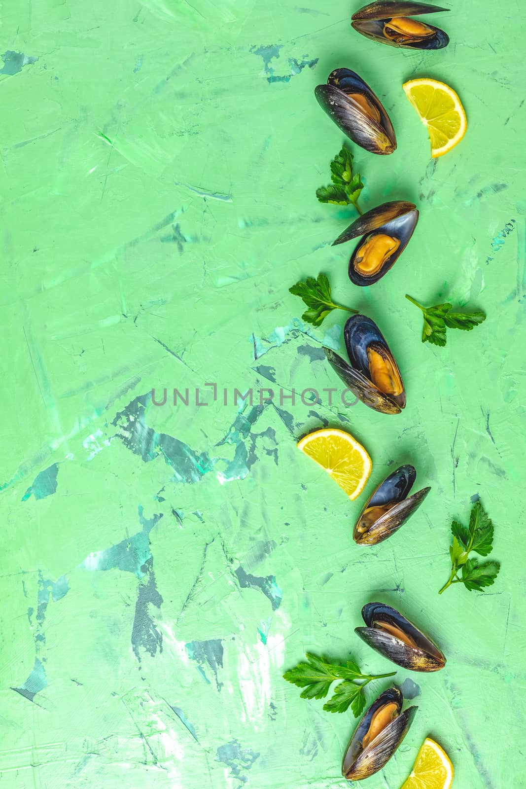 Seafood mussels with lemon and parsley on green concrete table surface, top view, copy space for you text