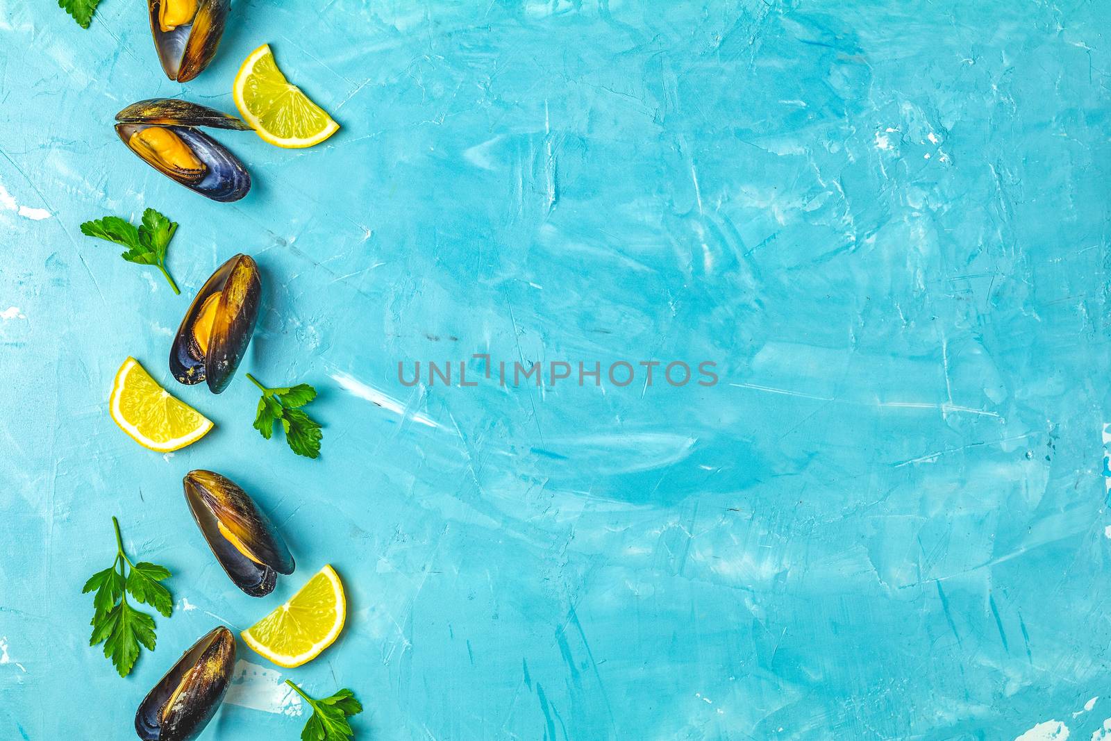 Seafood mussels with lemon and parsley on light blue concrete table surface, top view, copy space for you text