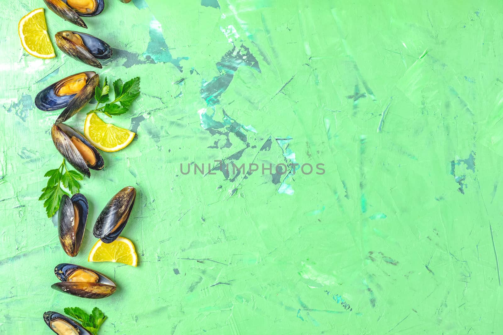 Seafood mussels with lemon and parsley on green concrete table surface, top view, copy space for you text